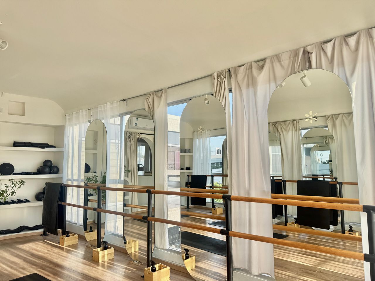 Sala de Plaza Constanza con luz natural, espejos en arco, barras de madera y tapetes.