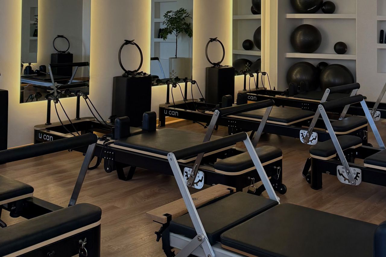 Sala de Plaza Marbella con reformers negros, espejos con luz cálida y pelotas de ejercicio en repisas.